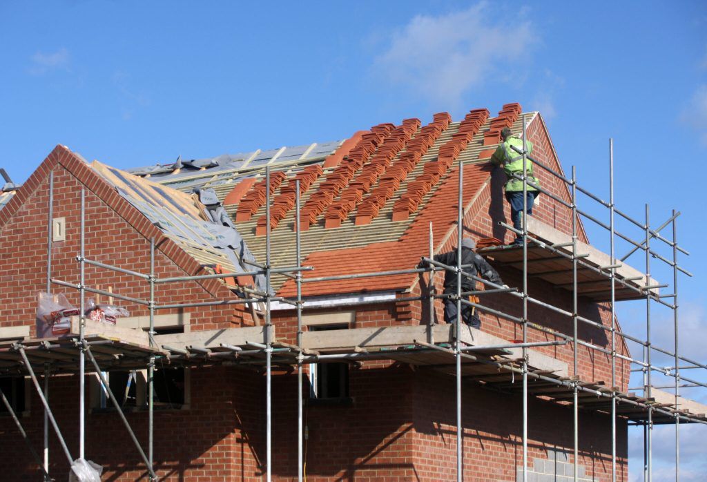 A man is working on the roof of a building under construction.