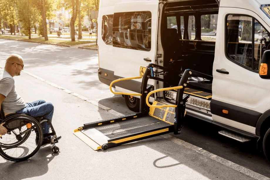 An empty wheelchair is getting lifted into a van using a vehicle lift system