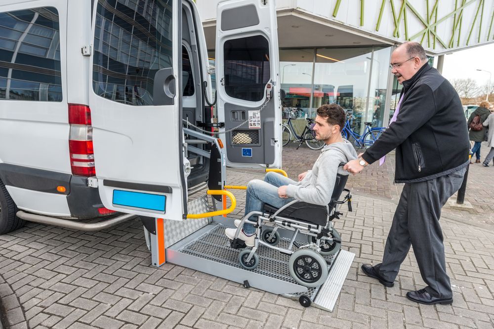 A man is pushing a man in a wheelchair into a van.
