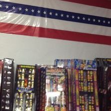 A bunch of fireworks are sitting on a table under an american flag.