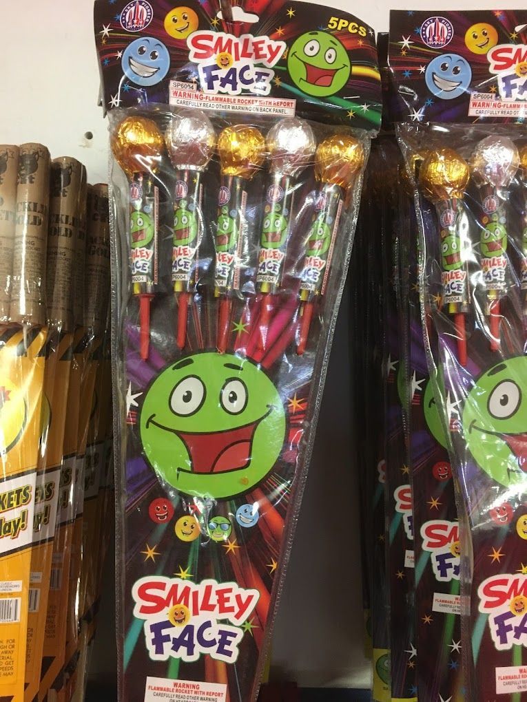 A bunch of smiley face fireworks are sitting on a shelf.