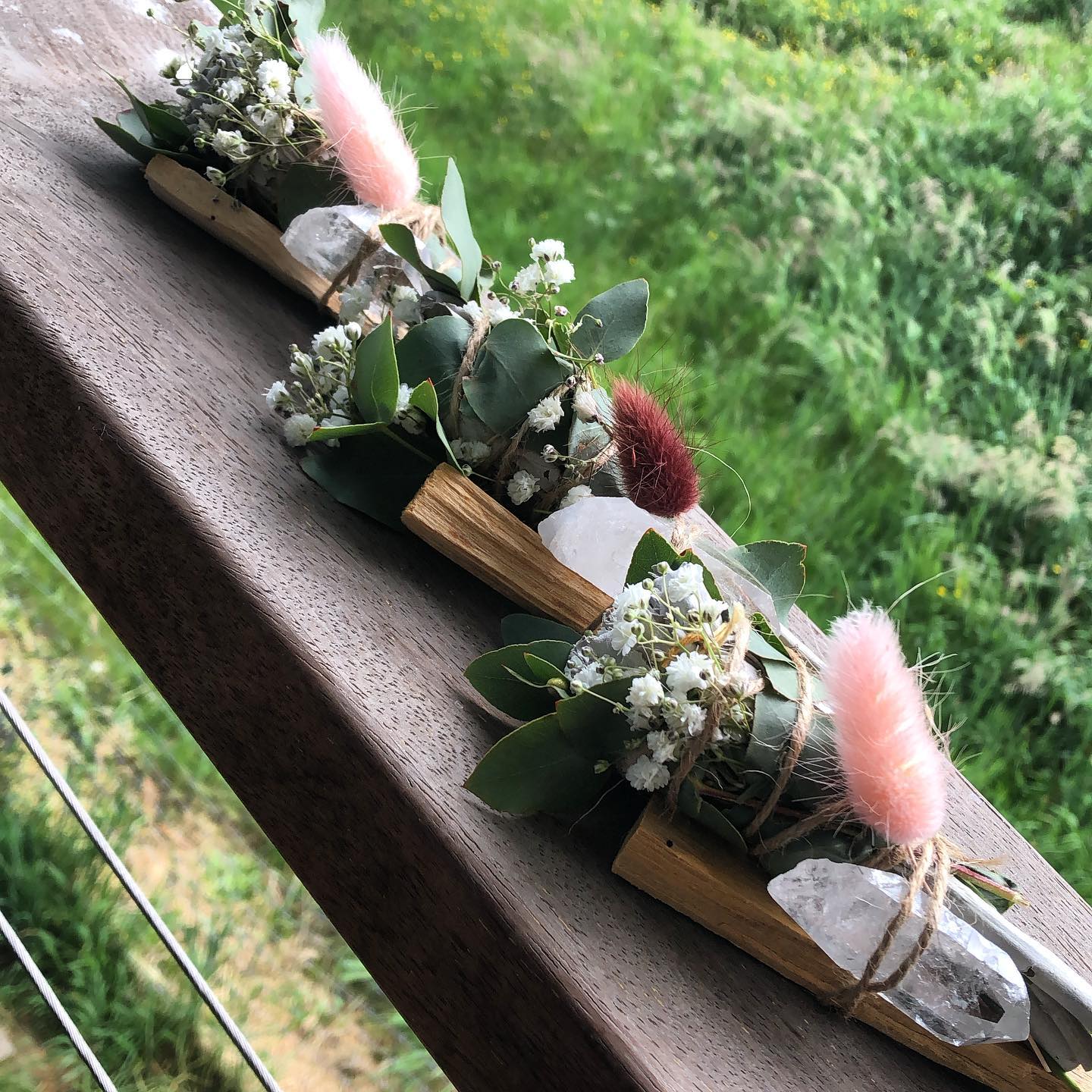 A wooden railing with flowers and crystals on it