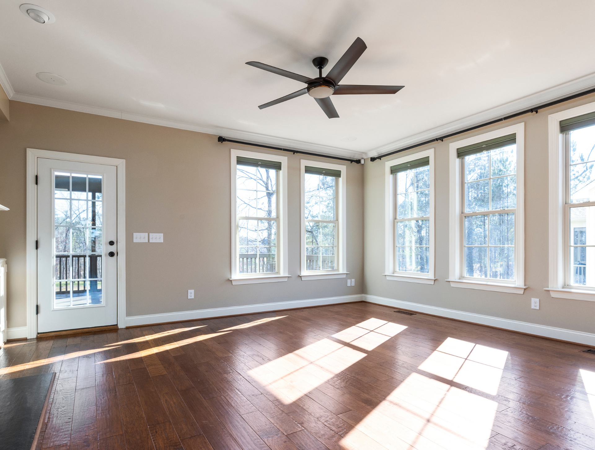 An empty living room with hardwood floors and a ceiling fan.