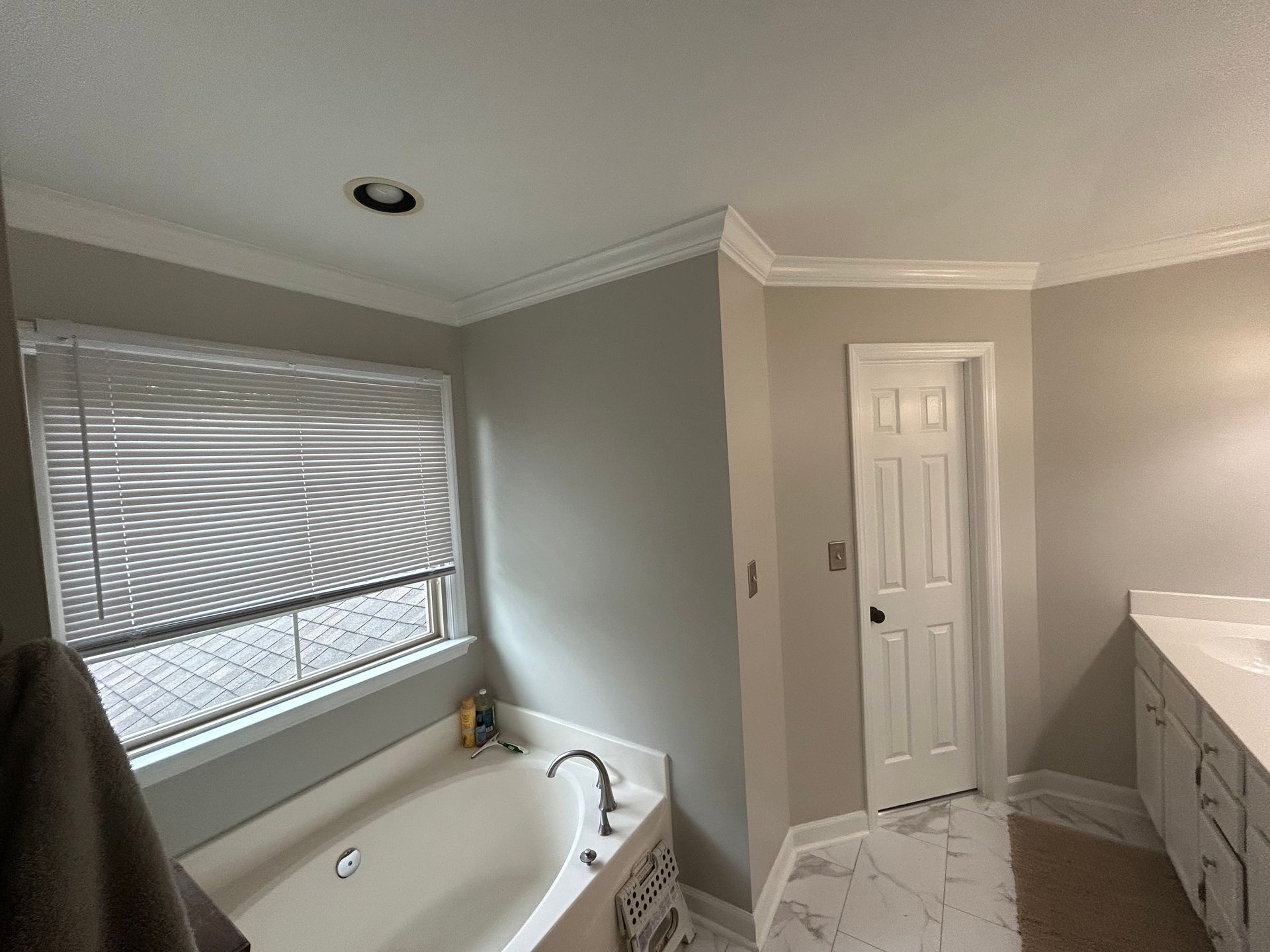 A bathroom with a tub , sink , and window.