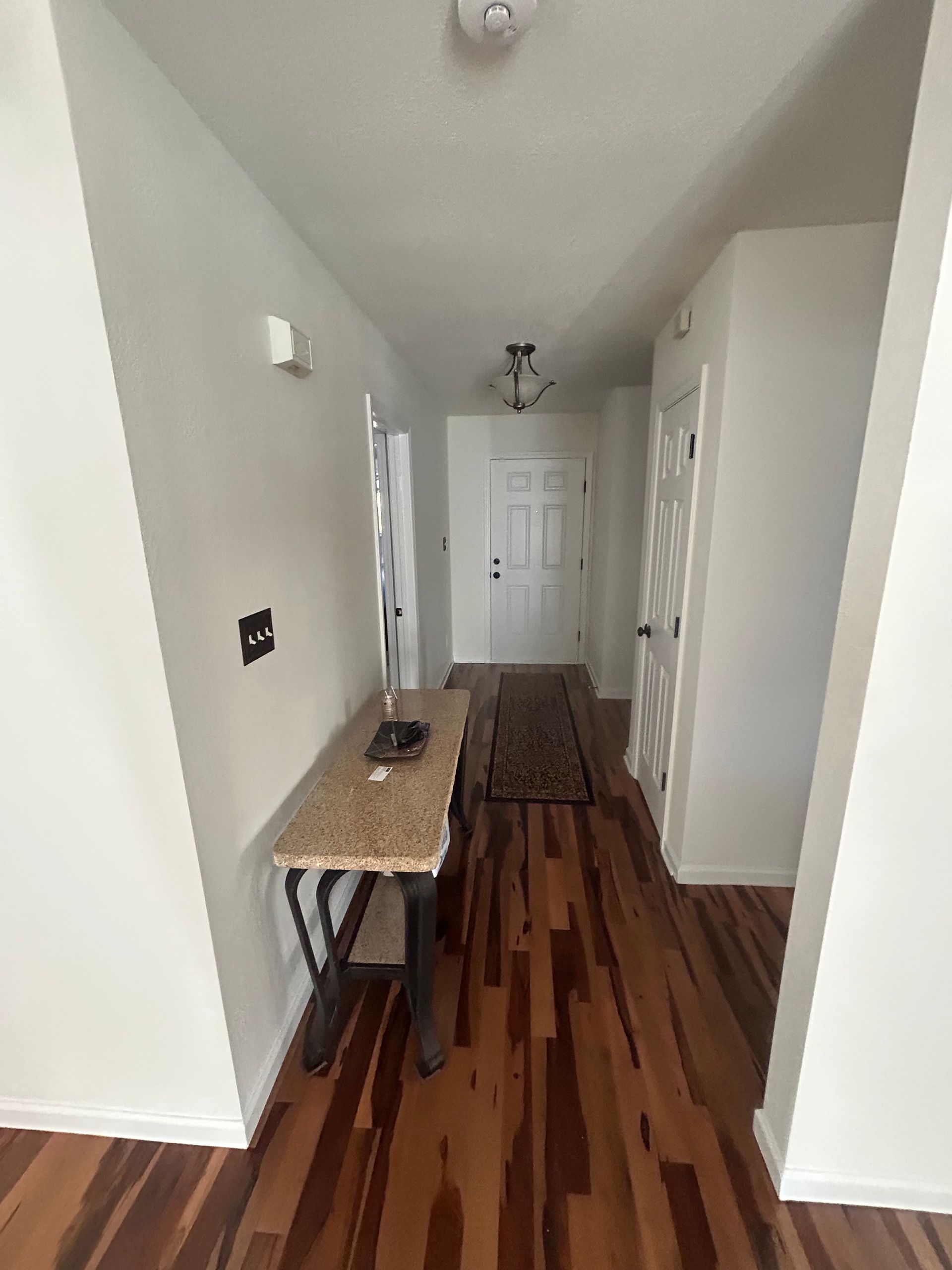 A hallway with hardwood floors and a table in the middle of it.