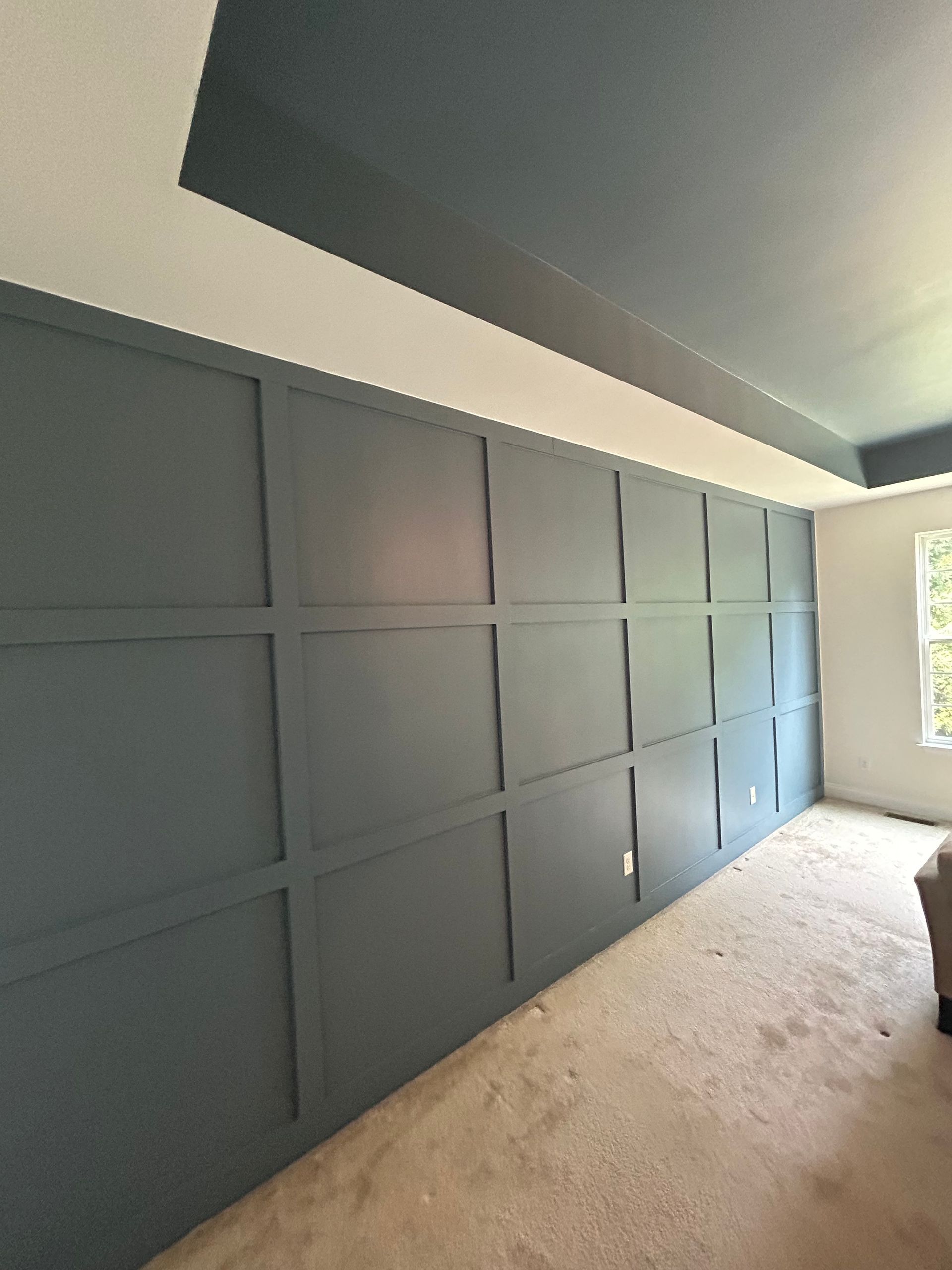 A living room with a couch and a large wall with a window.