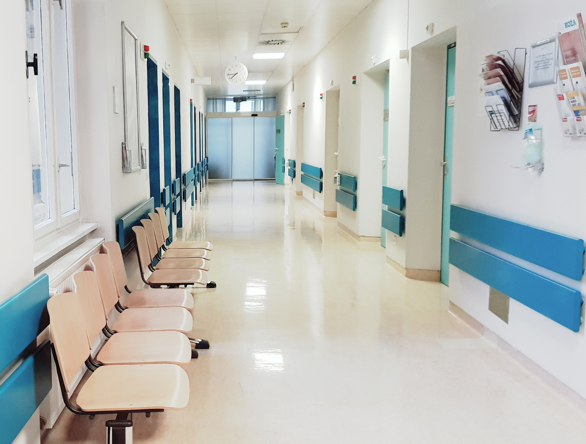 There are a lot of chairs in the hallway of a hospital.