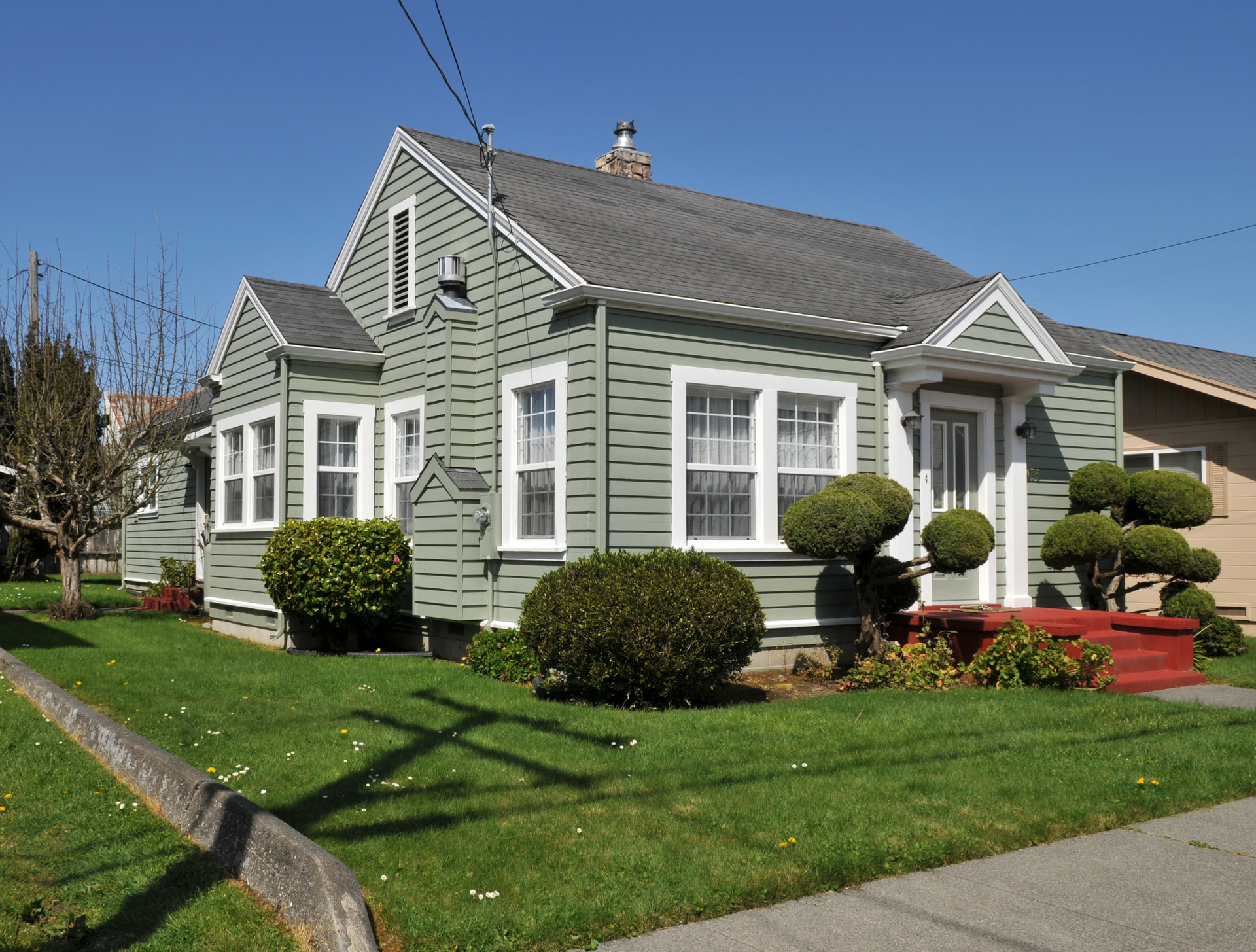 A green house with white trim and a gray roof