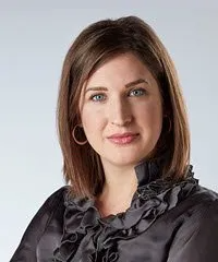 A woman is wearing a black ruffled blouse and earrings.