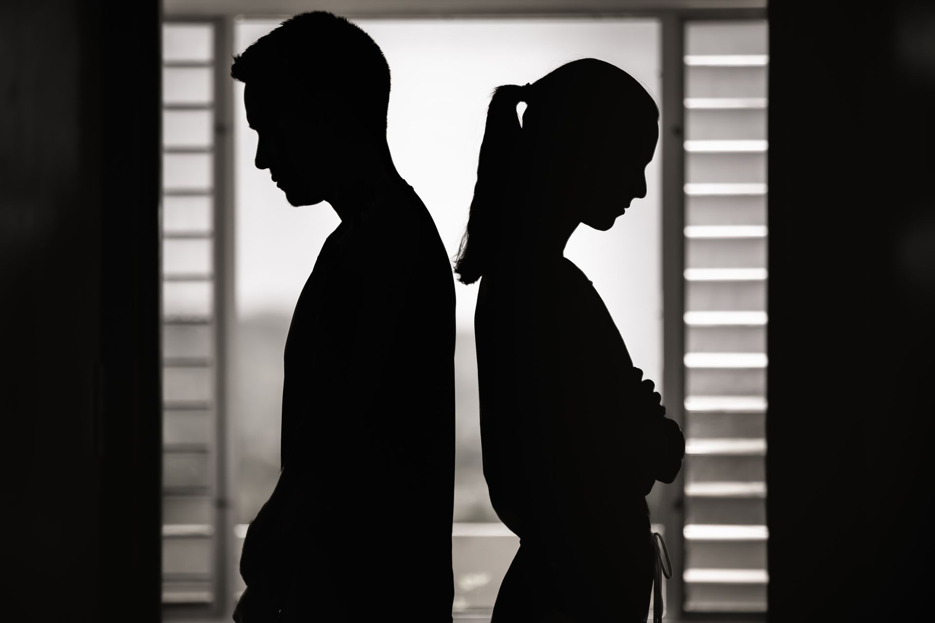 Couple in darkened room with backs to one another.