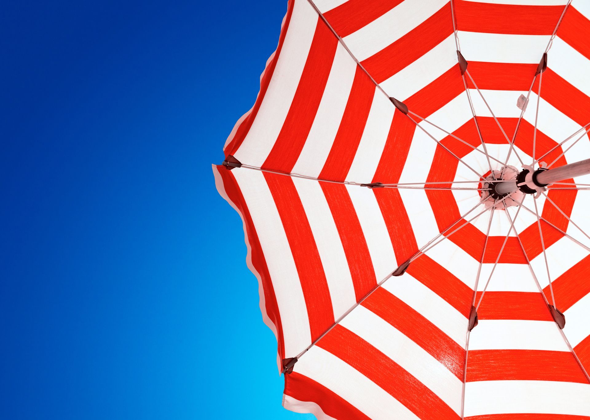 Red and white umbrella against blue sky