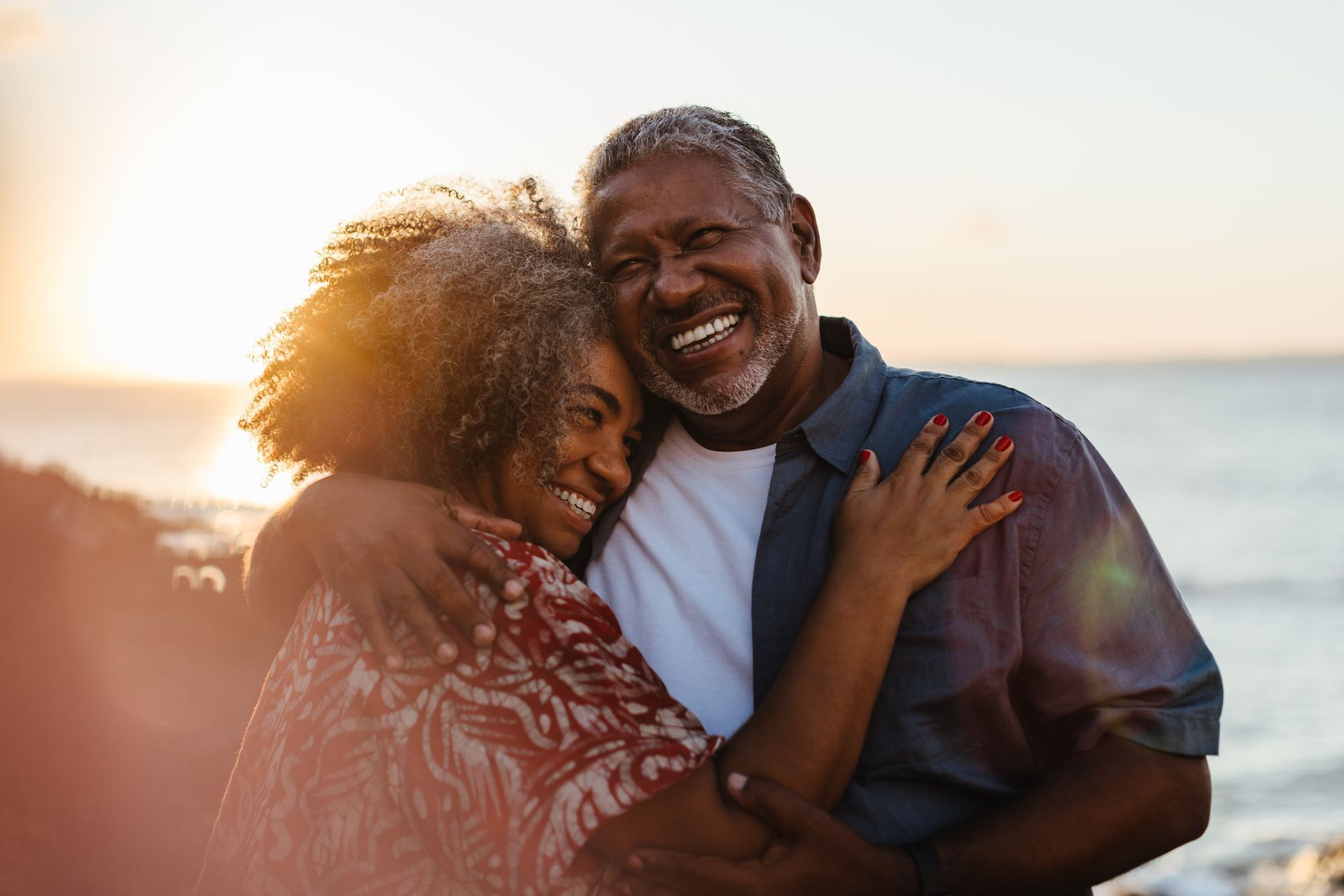 older couple in a warm embrace by the ocean