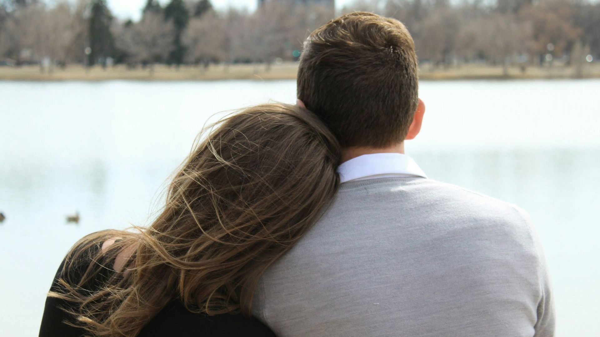 A man and a woman are sitting next to each other and looking at the water.