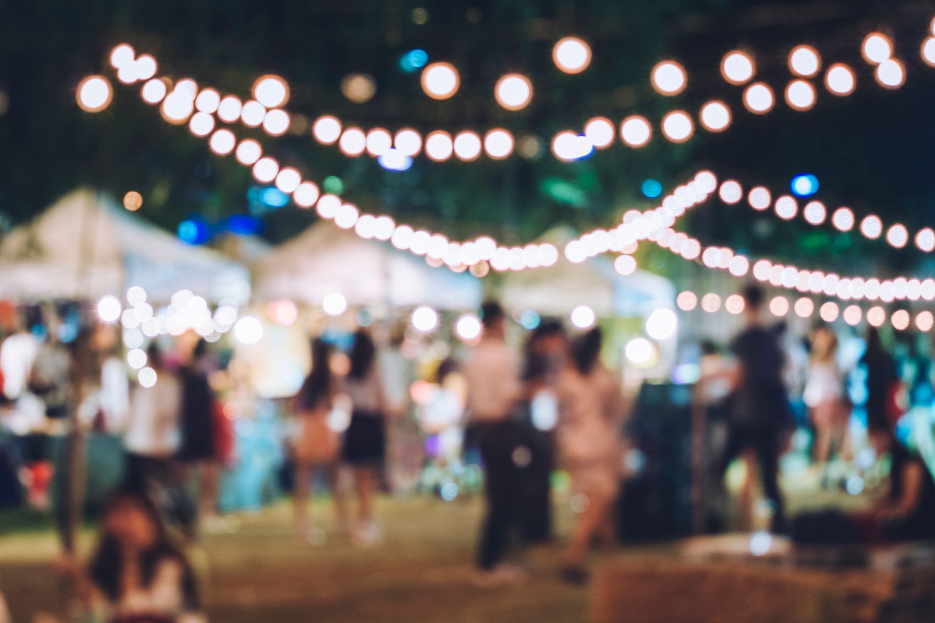 people dancing in a backyard party under strings of lights