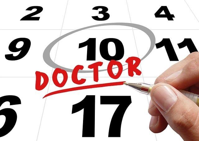 A person is writing the word doctor on a calendar
