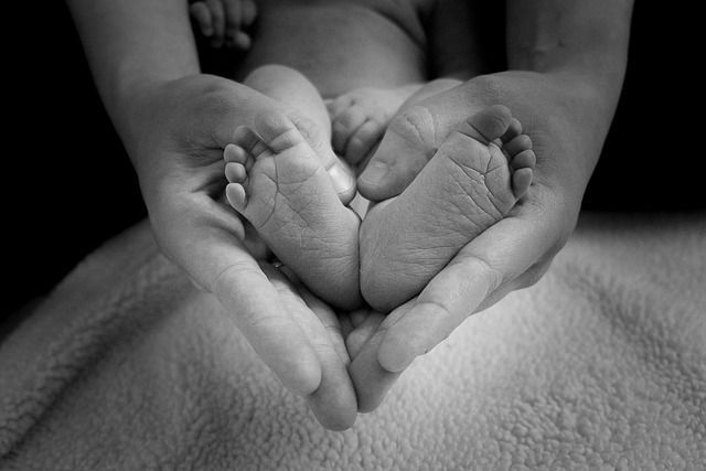 A person is holding a baby 's feet in their hands in a heart shape.