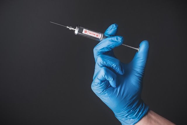 A person wearing blue gloves is holding a syringe.