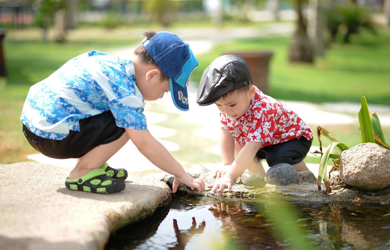 Two young boys are playing in a pond.