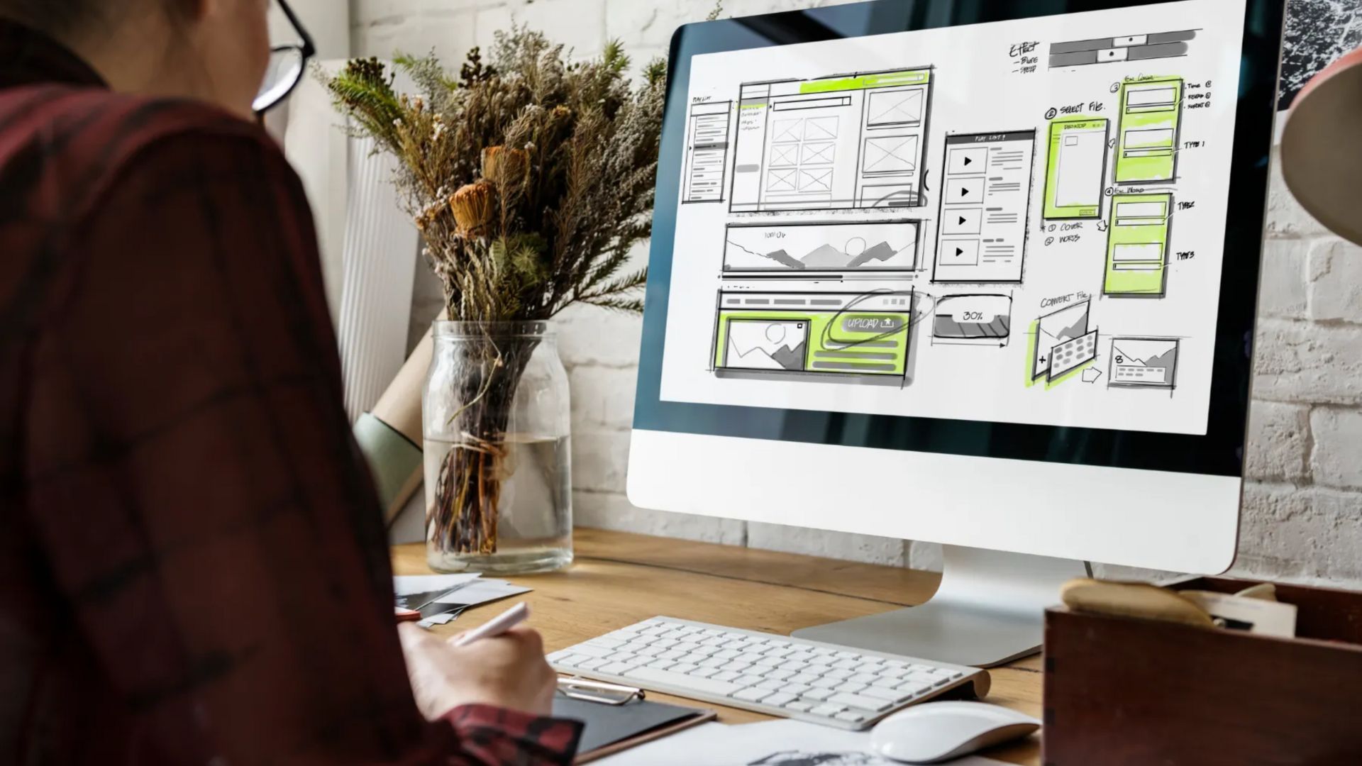 Person sketching website design on computer.