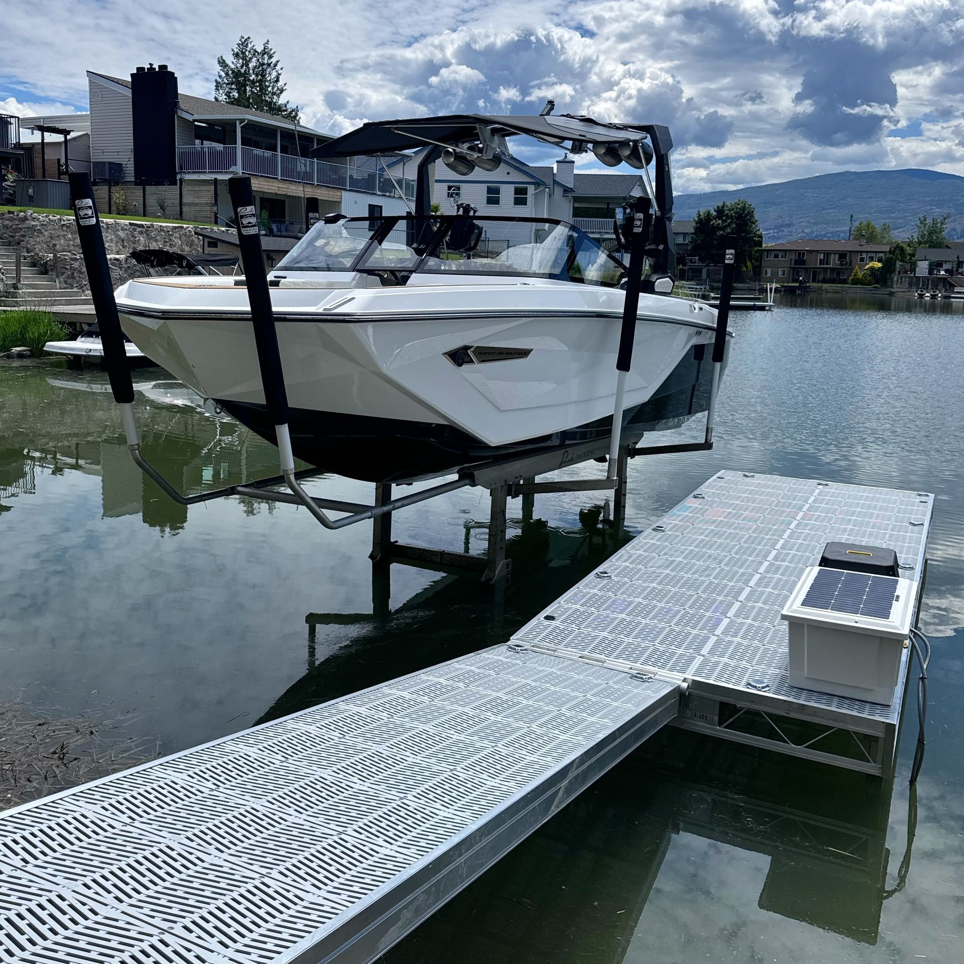 A boat is on a lift next to a dock on a lake.