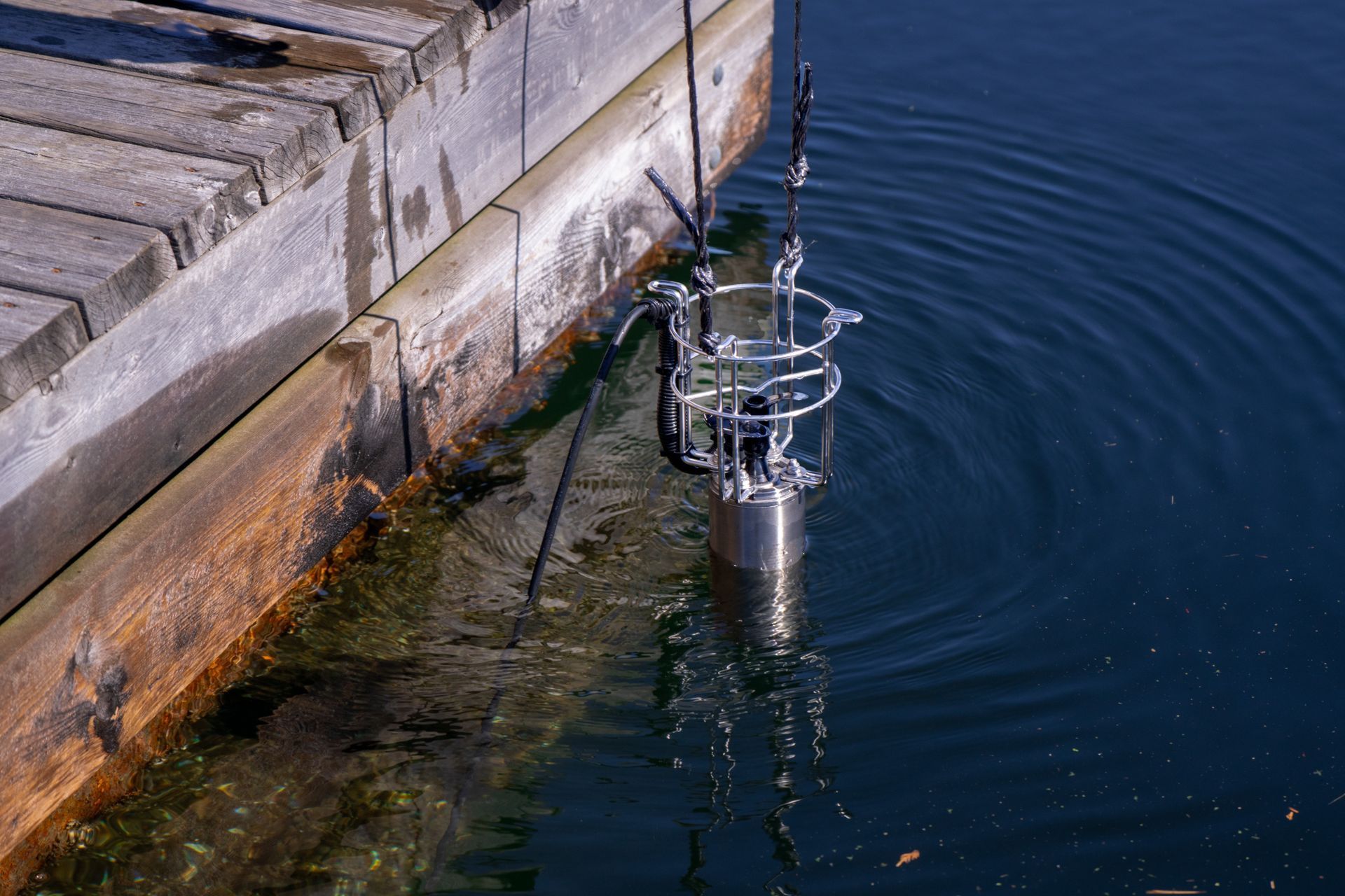 A water circulator is floating in the water near a wooden dock.