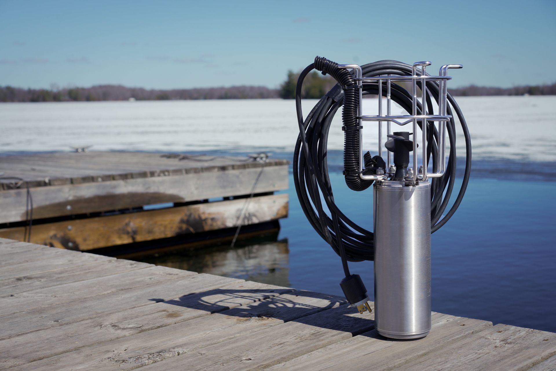 A stainless steel device is sitting on a dock next to a body of water.