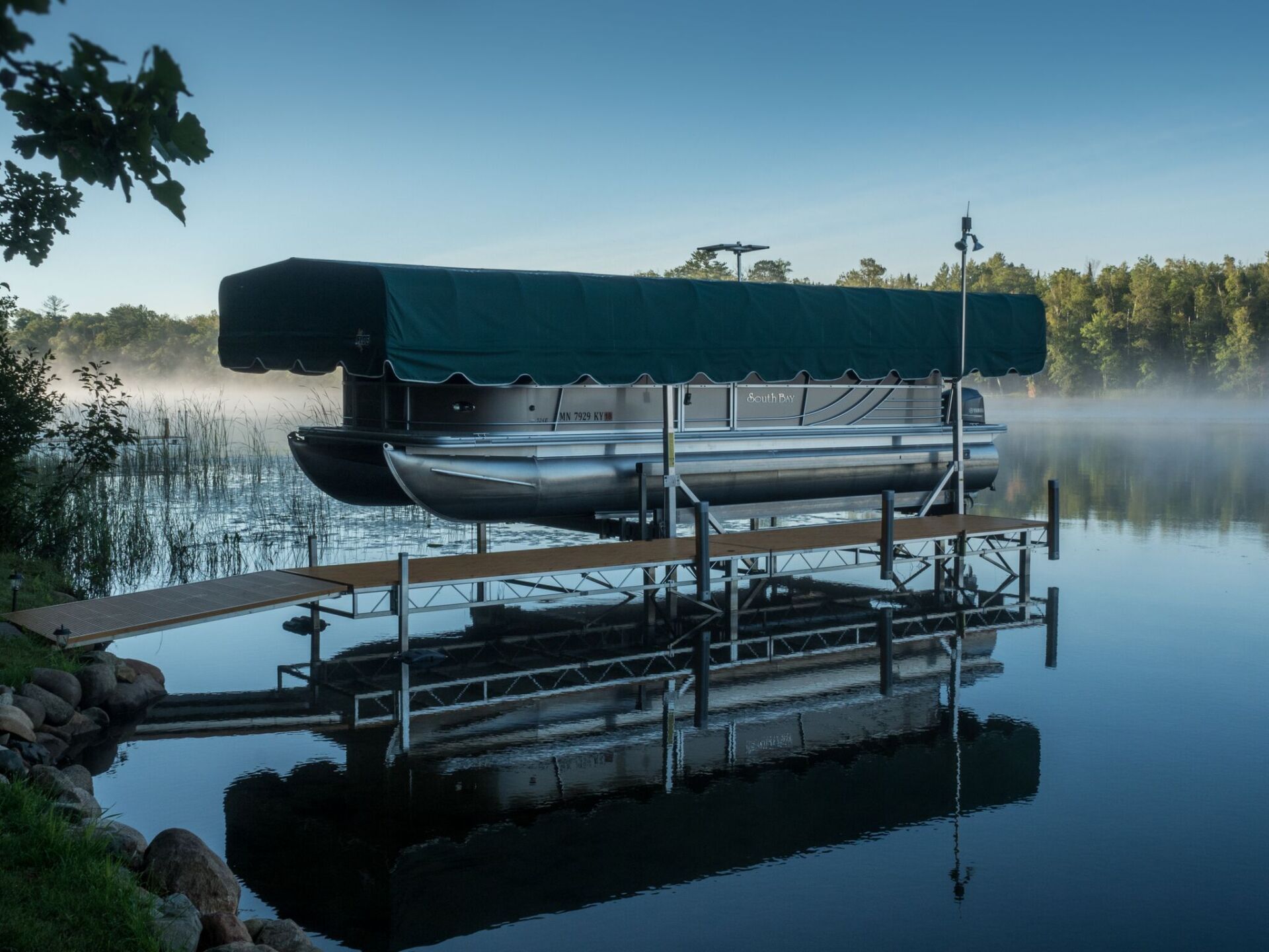 A pontoon boat is docked at a dock on a lake.