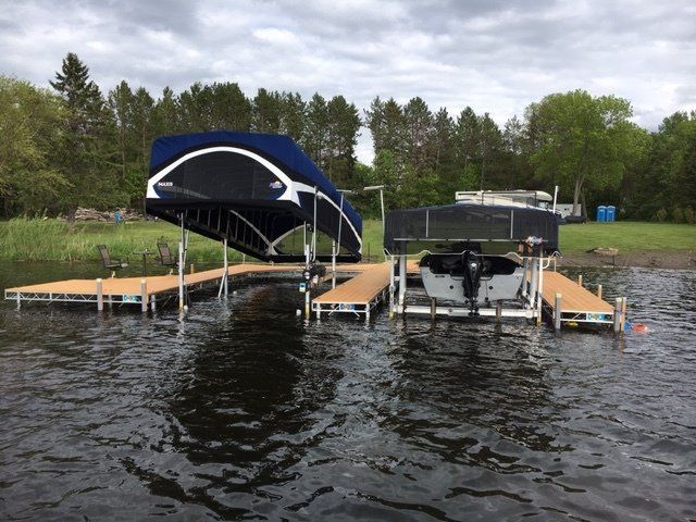 Two boats are docked at a dock on a lake.