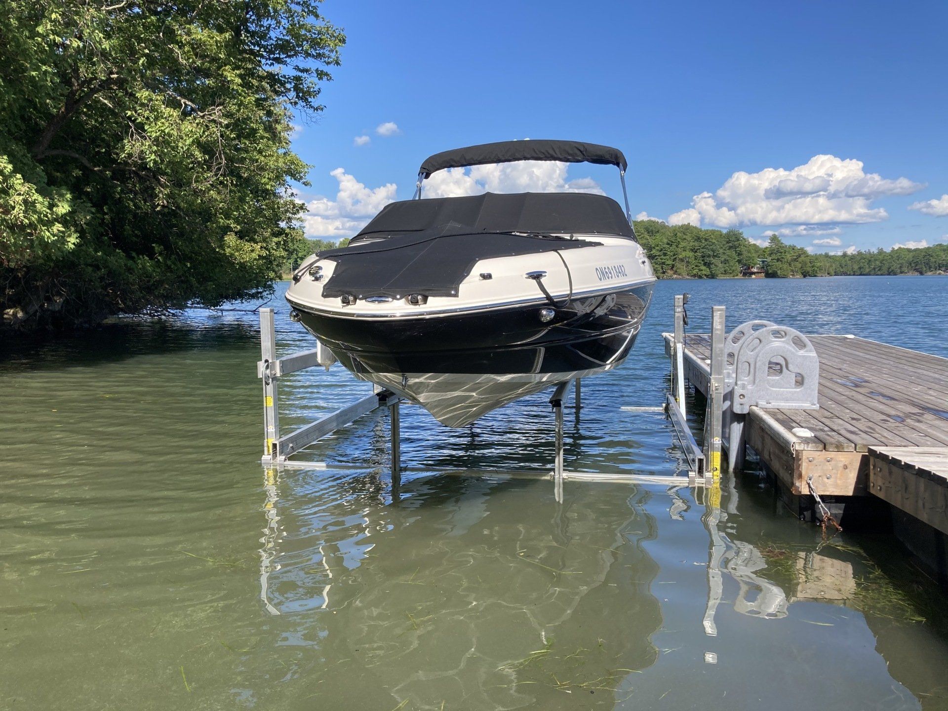 A boat is sitting on a lift in the water.