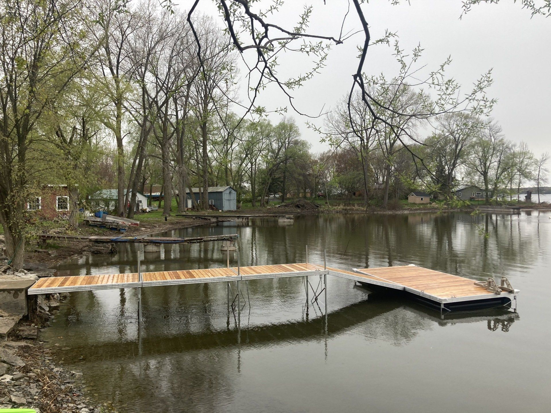 A wooden dock is in the middle of a lake surrounded by trees.