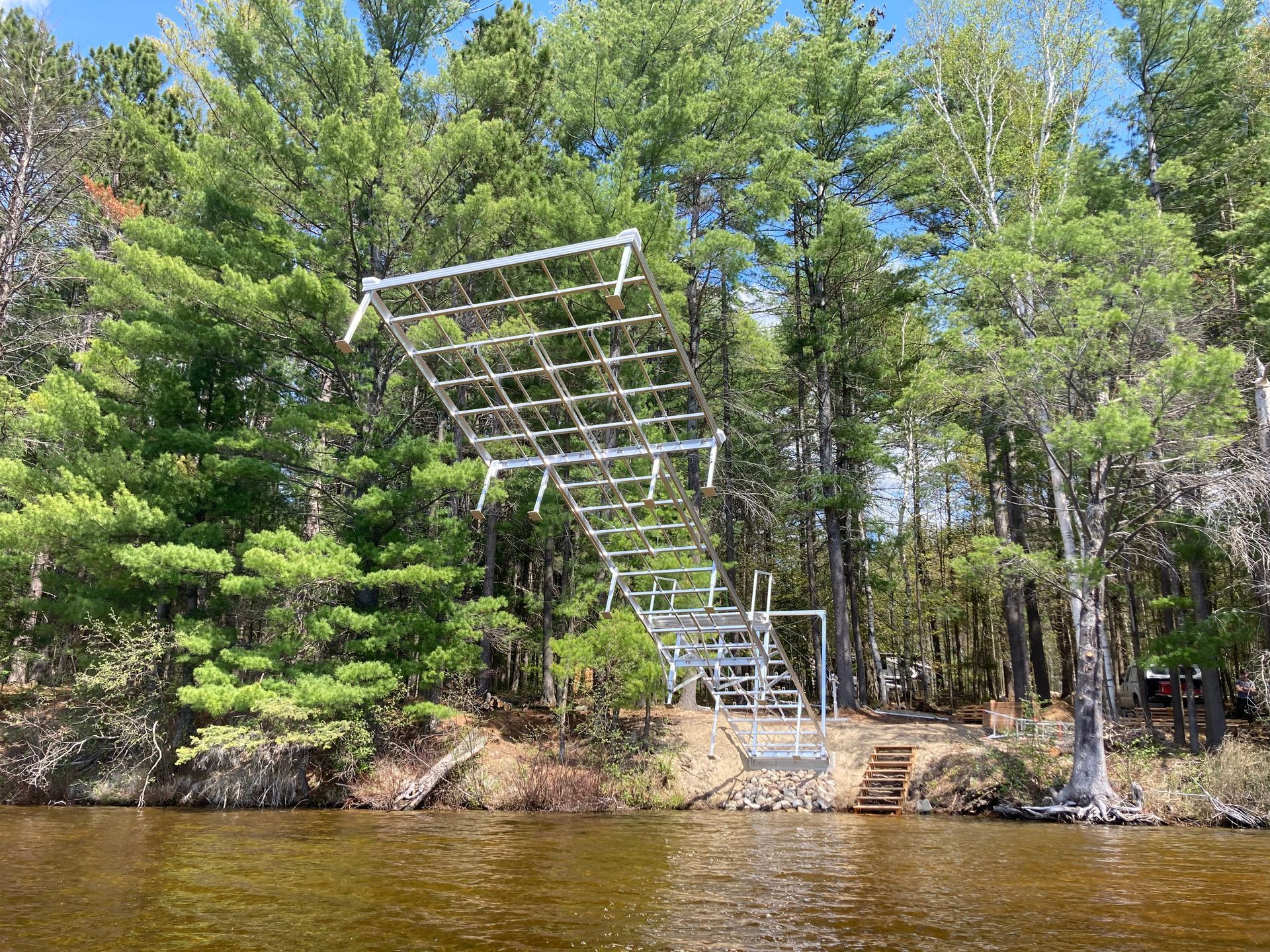 A ladder is hanging over a body of water surrounded by trees.