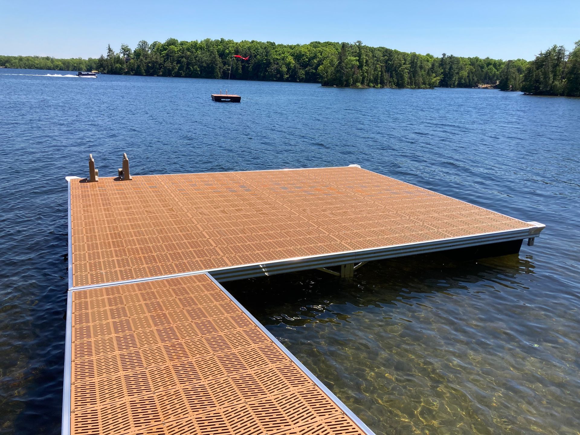 A dock in the middle of a lake with a boat in the background.
