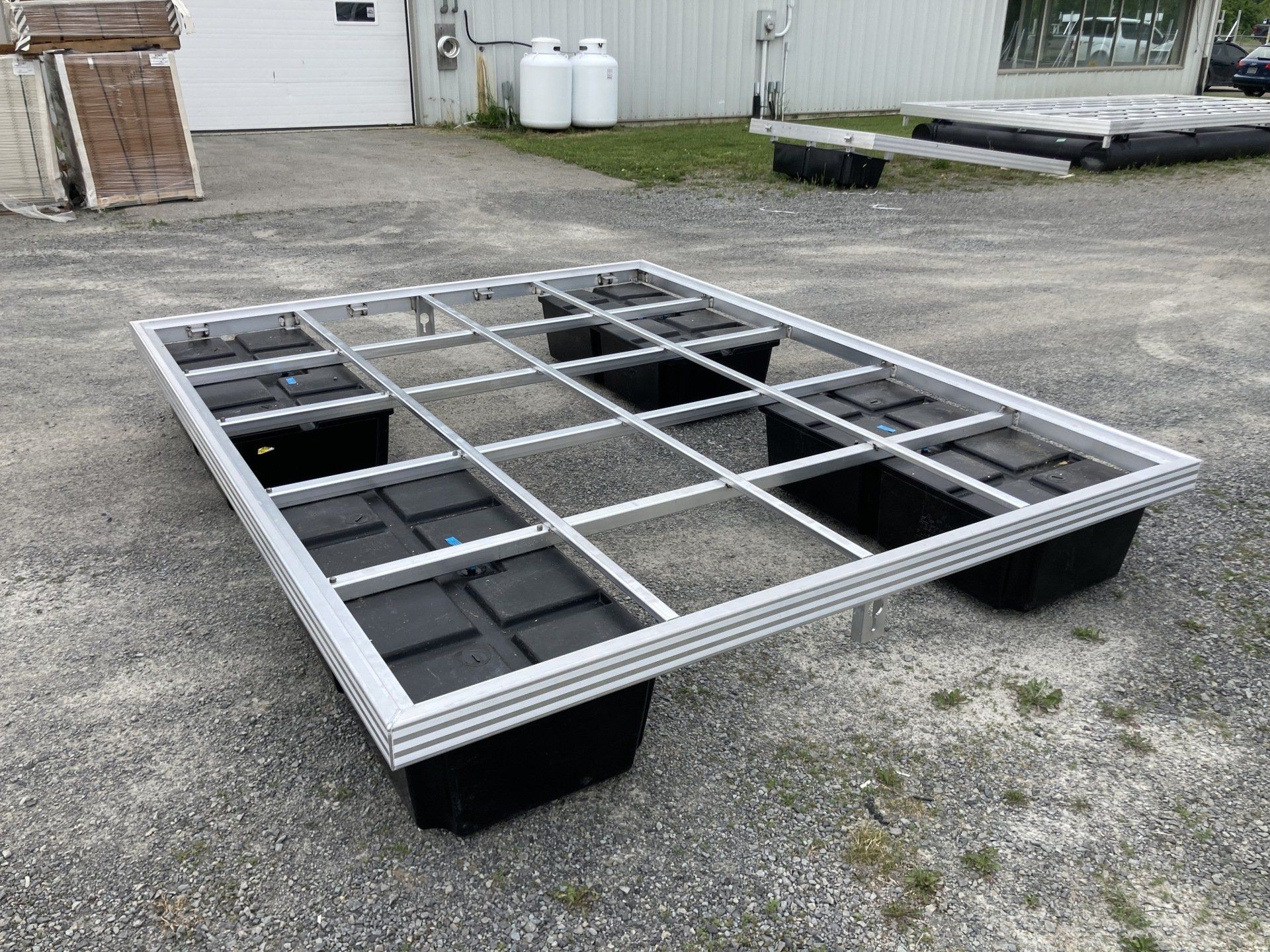 A metal frame with black containers on top of it is sitting on the ground.
