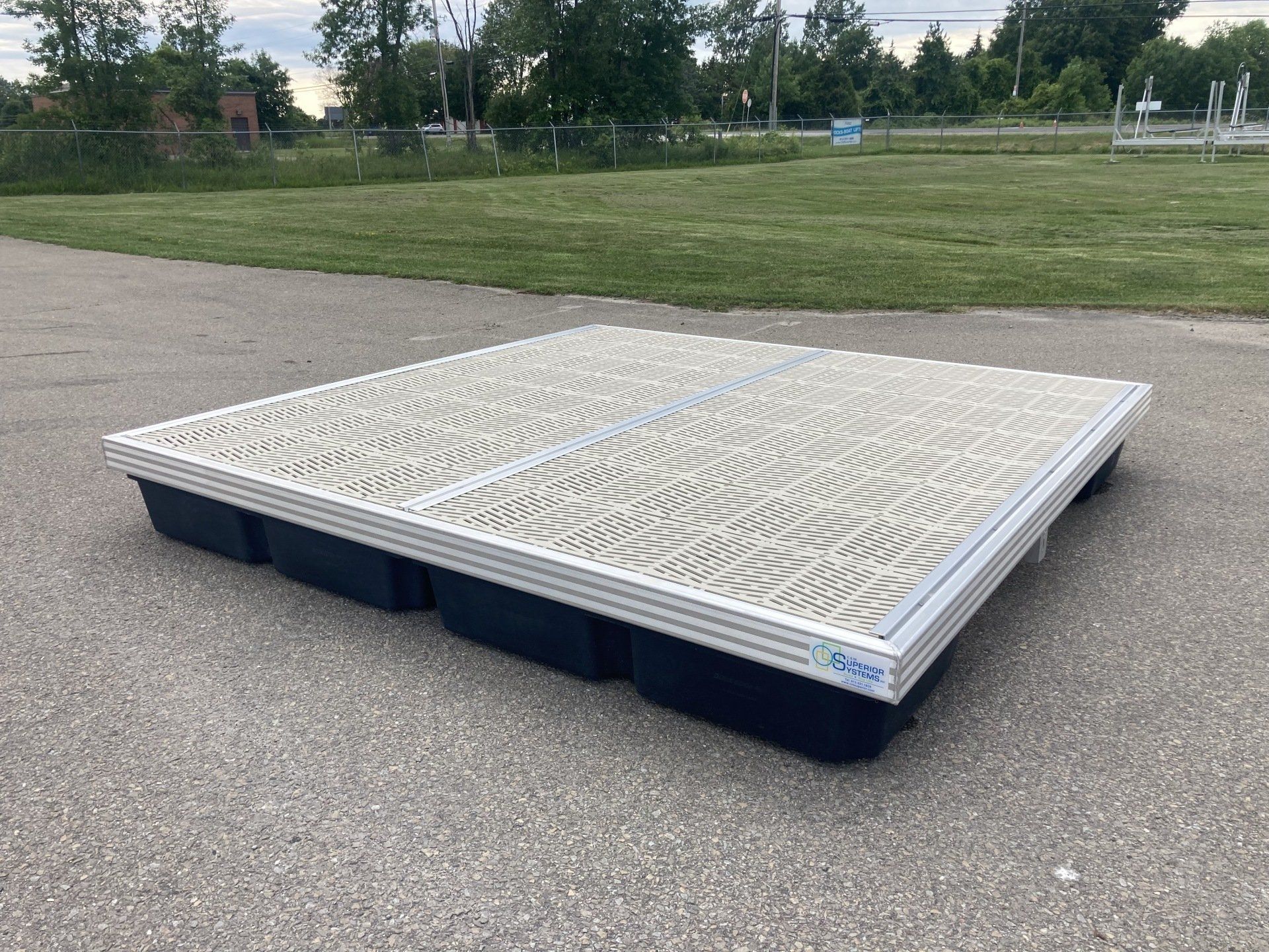 A large pallet is sitting on the side of a road next to a grassy field.