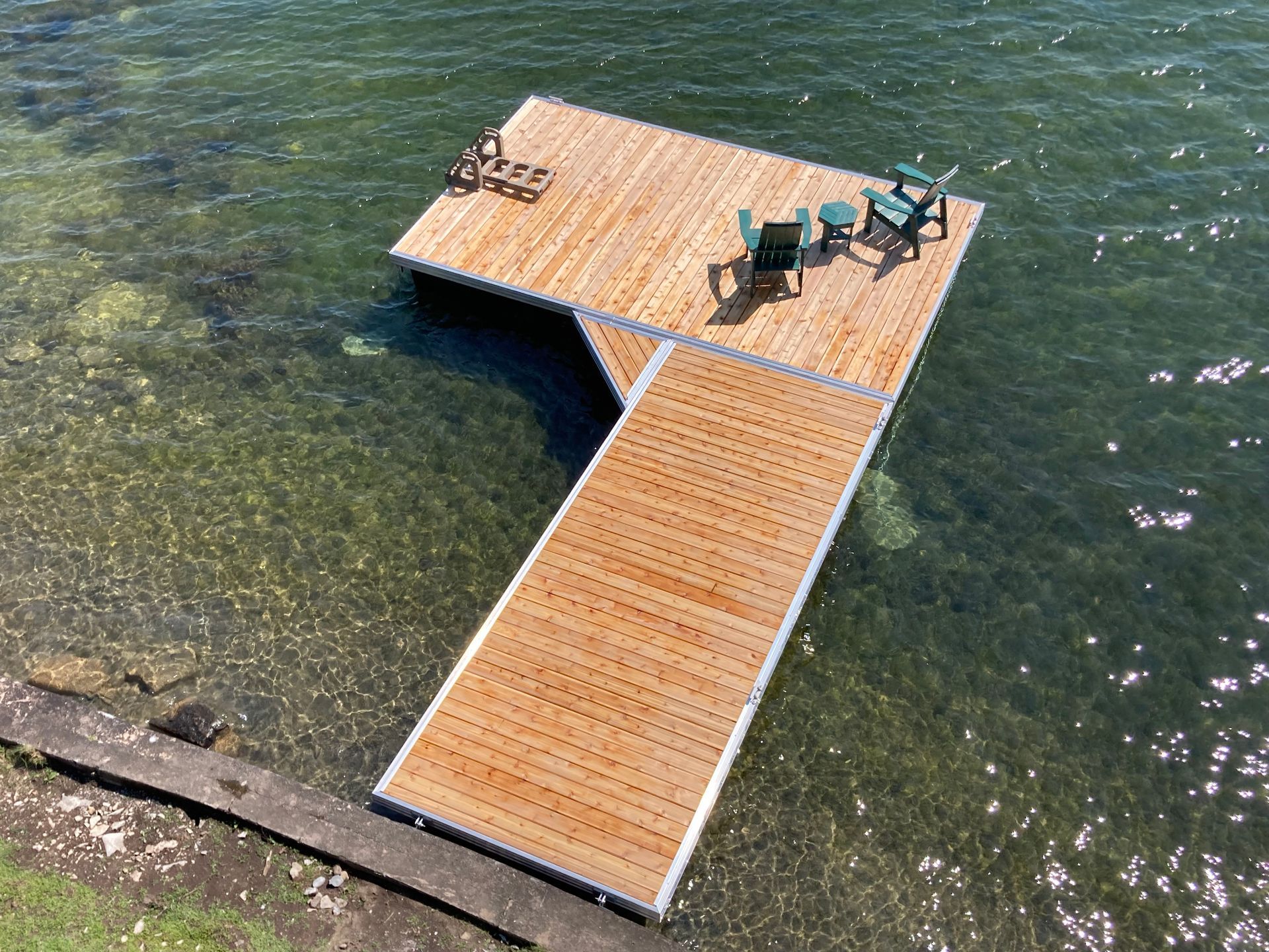 An aerial view of a wooden dock with chairs on it in the water.