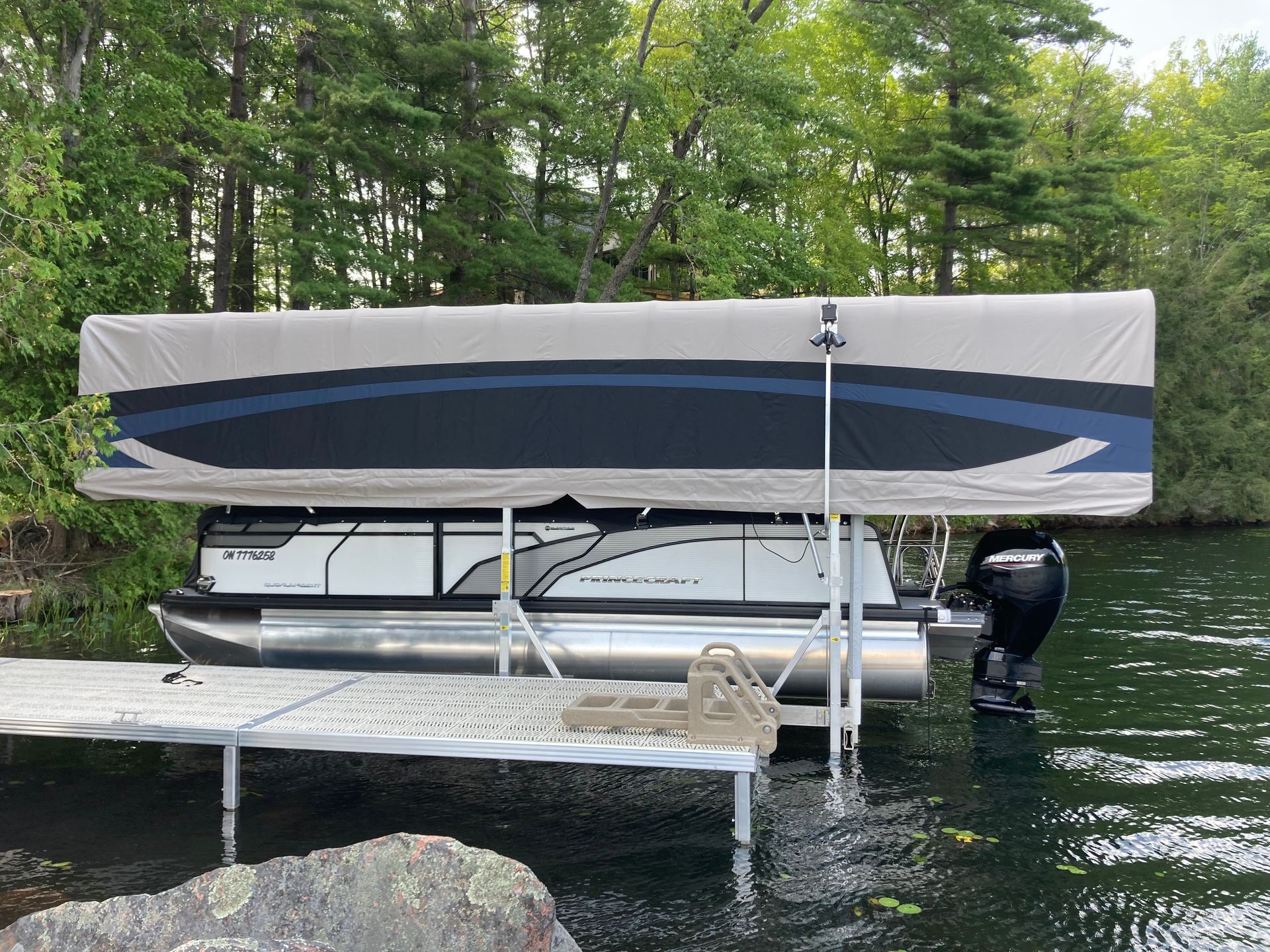 A pontoon boat is docked at a dock on a lake.