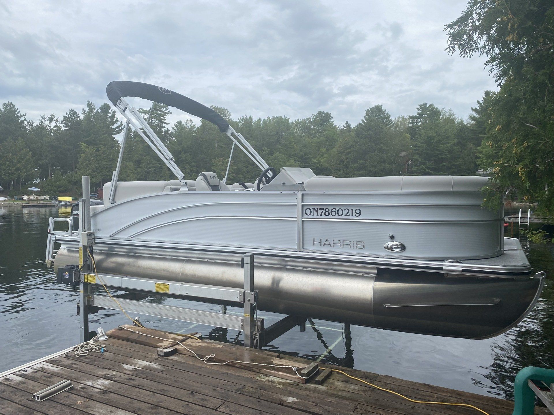 A pontoon boat is docked at a dock on a lake.