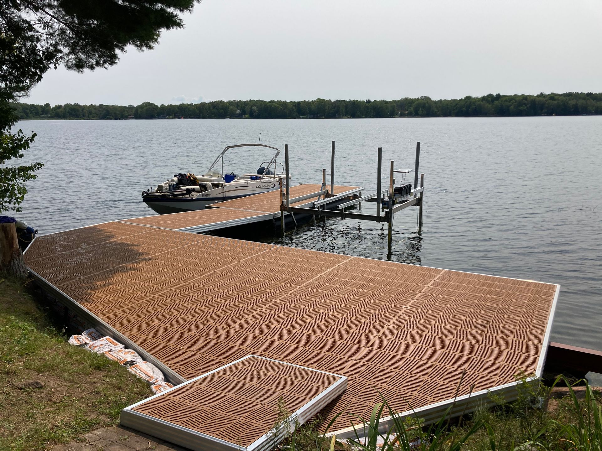 Dock on Shoreline. Boat secured to dock. Boat lift visible.
