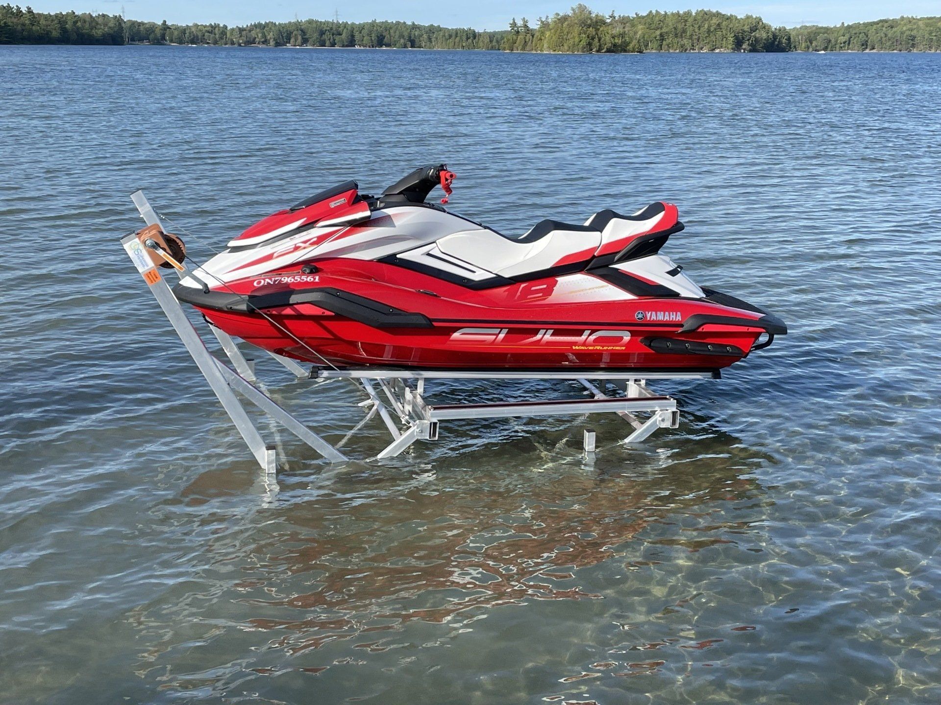 A red and white jet ski is sitting on top of a dock in the water.