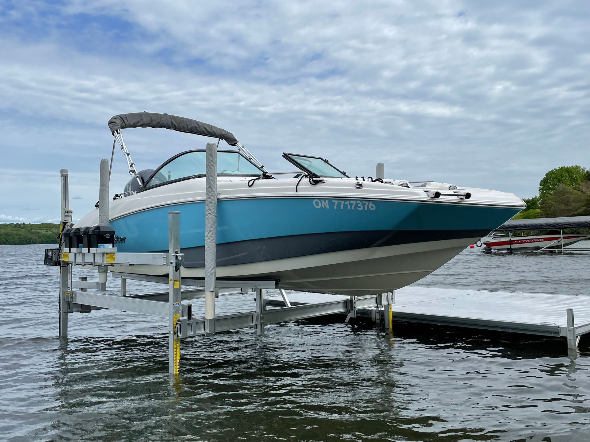 A blue and white boat is docked at a dock on a lake.