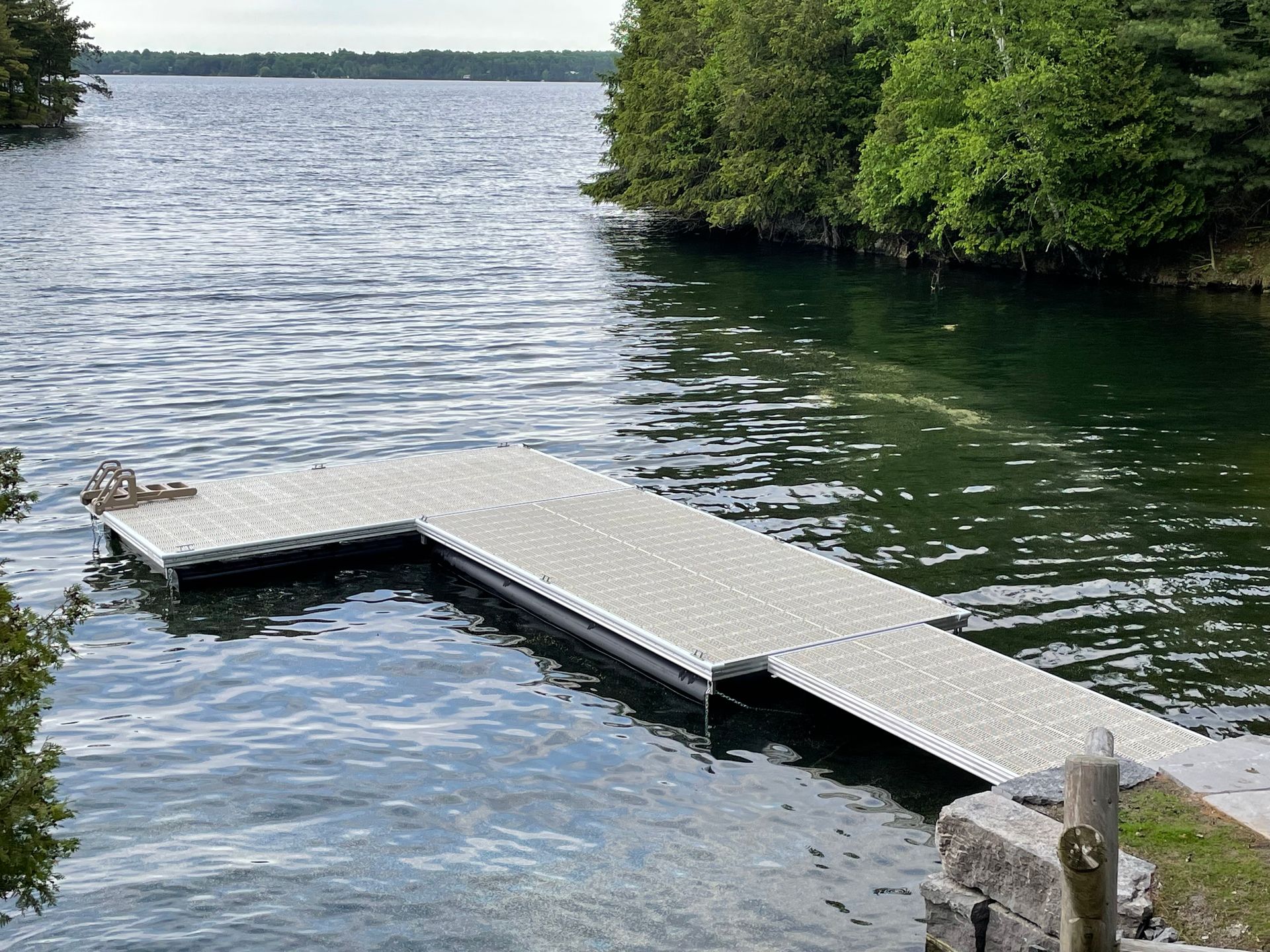 A dock in the middle of a lake with trees in the background