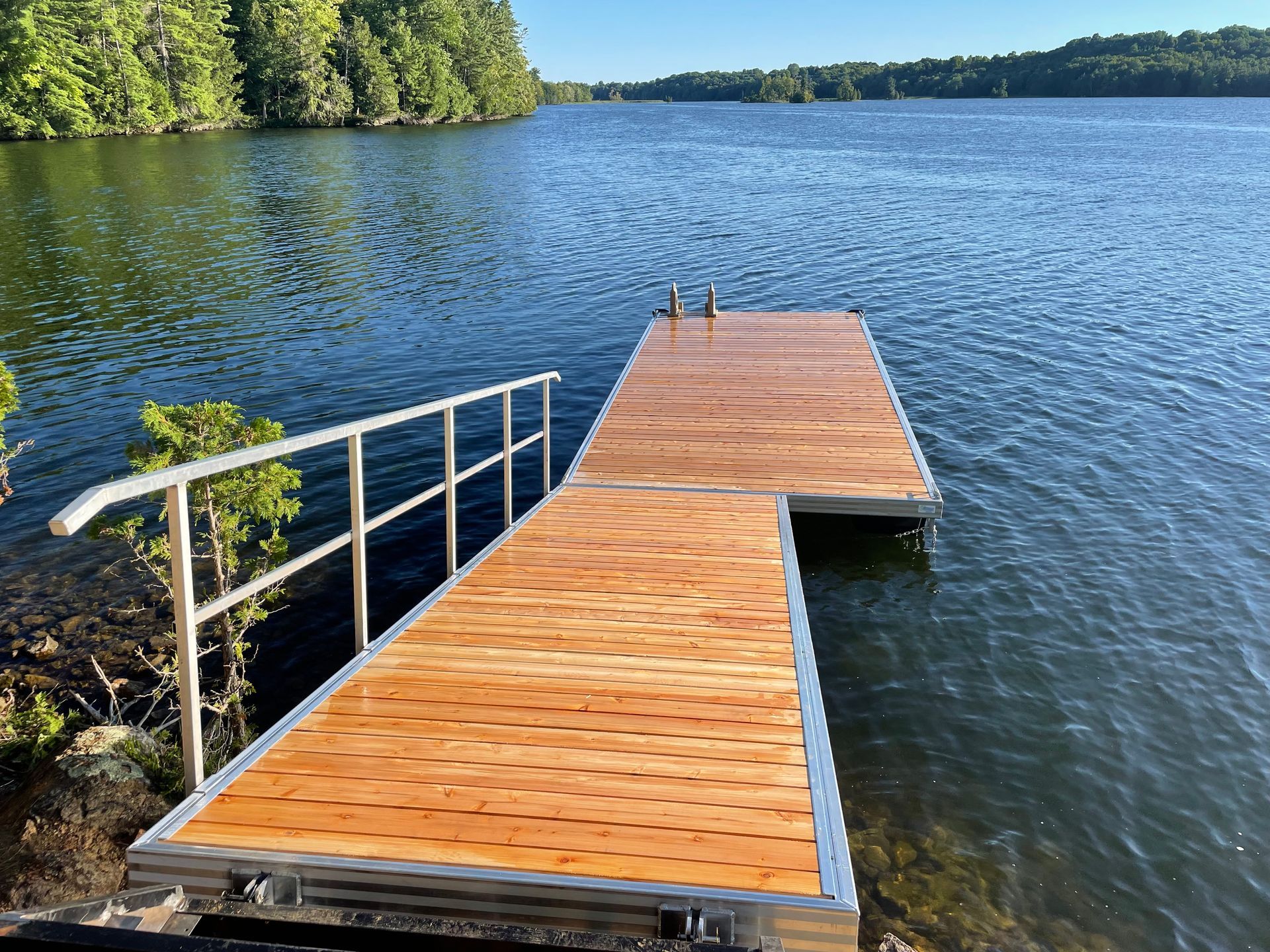 A wooden dock with a metal railing is in the middle of a lake.