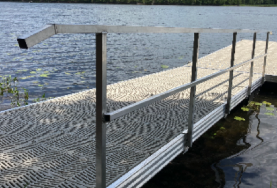 A dock with a metal railing leading to a body of water.