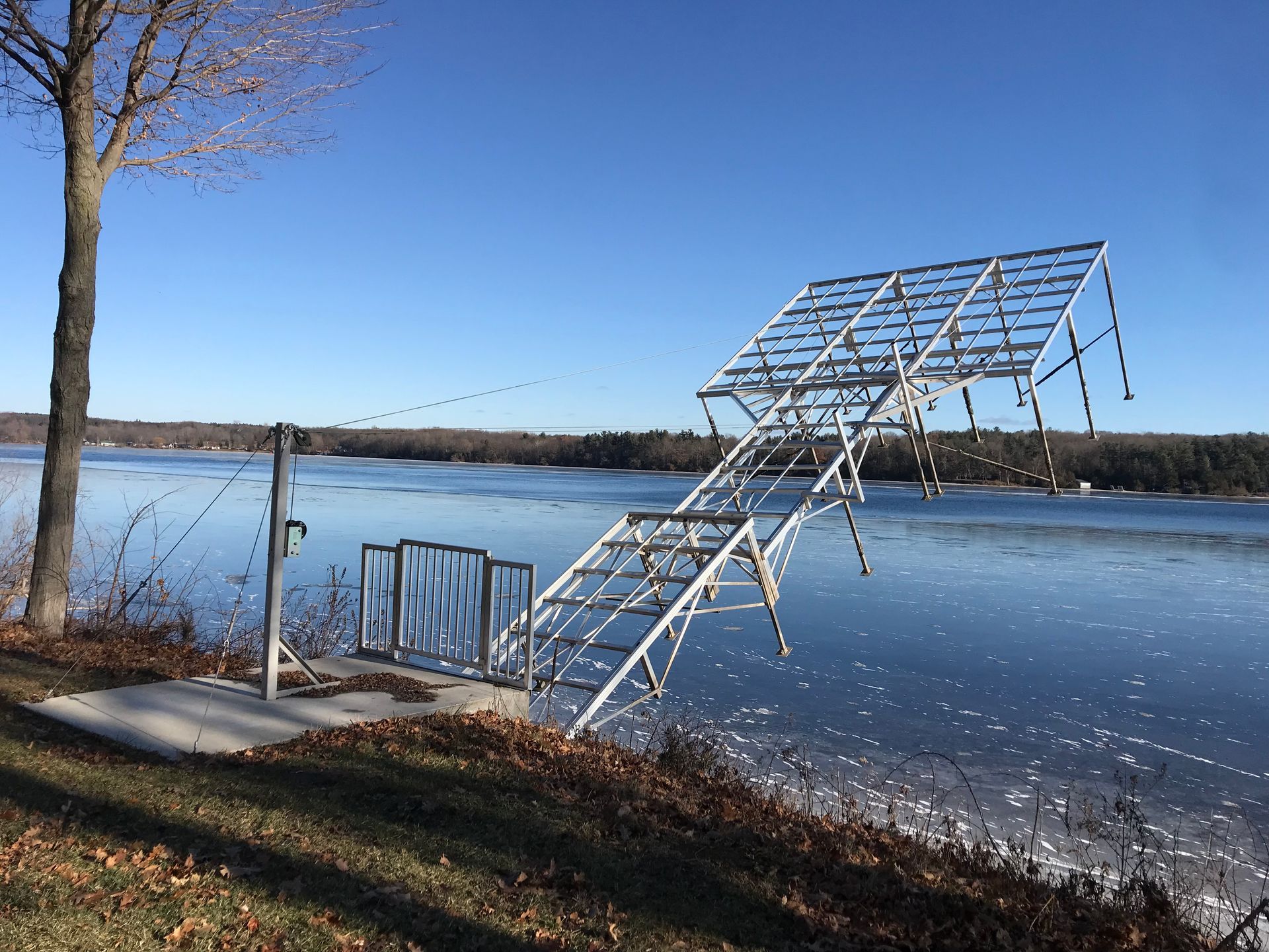 A metal structure is sitting on the shore of a lake.