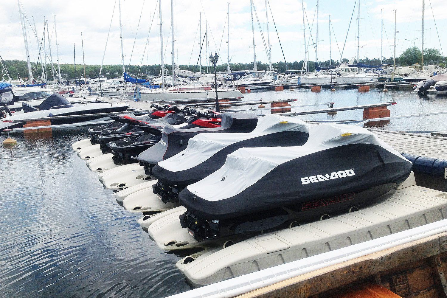A row of jet skis are sitting on a dock in a marina.