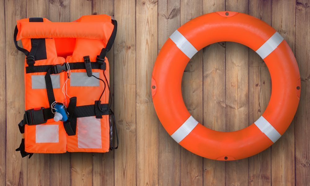 Canadian-approved lifejacket and orange lifebuoy ring displayed on a wooden dock