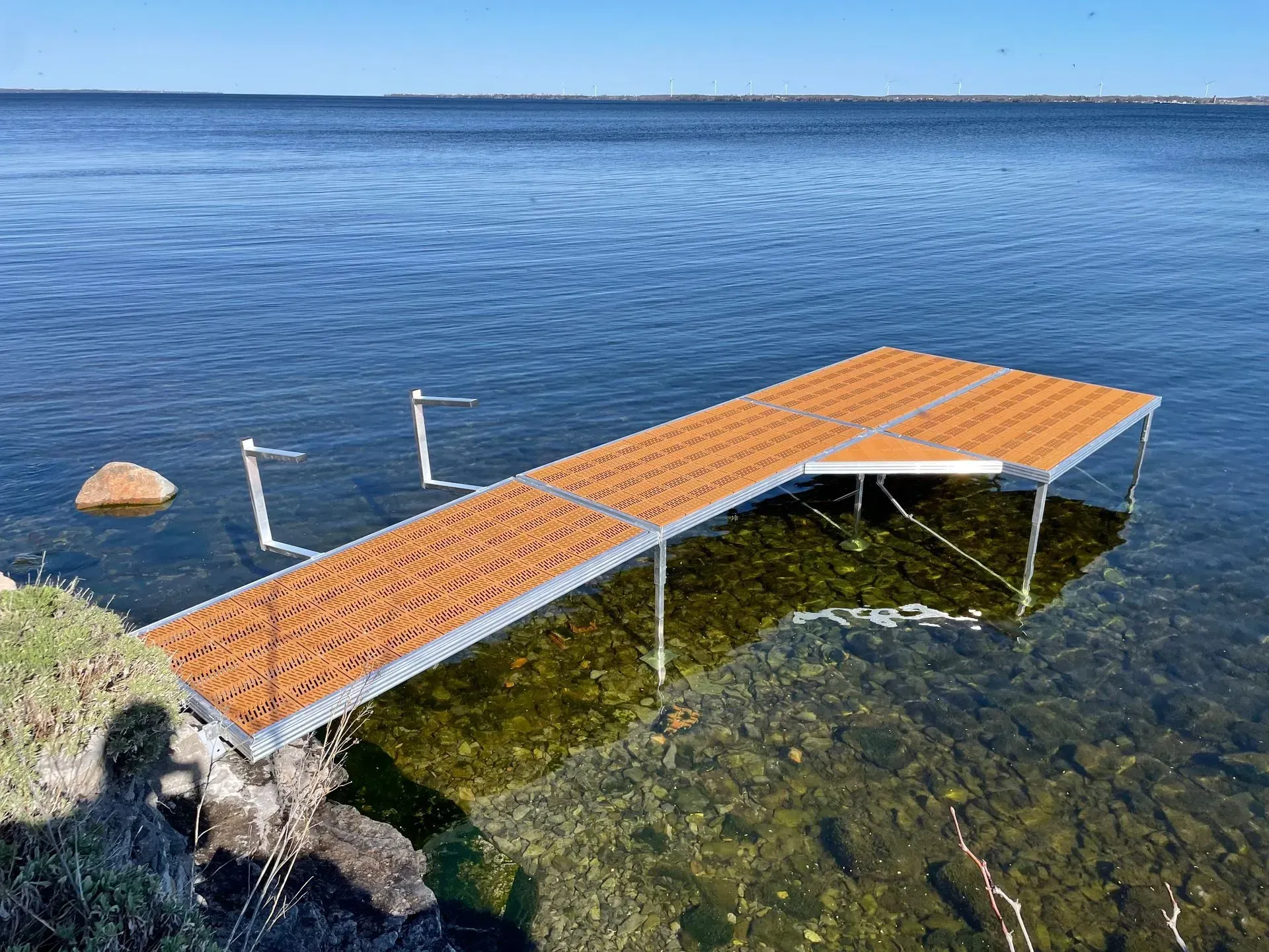 A boat is docked at a pole dock next to a lake.