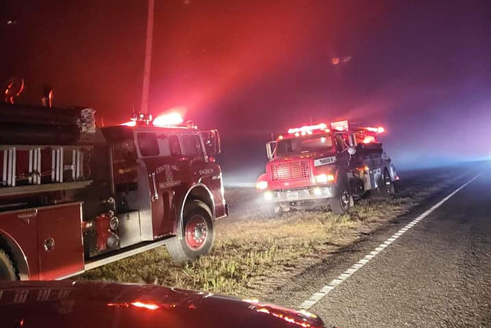 A fire truck is parked on the side of the road at night.