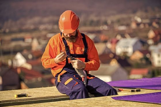 a man in an orange safety helmet sitting on a roof