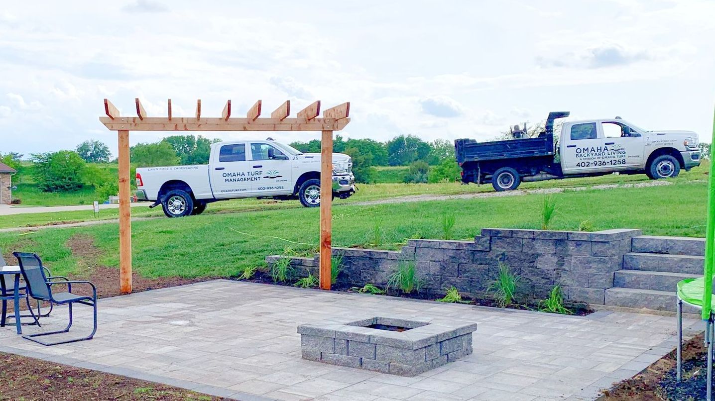 Two trucks are parked in a field next to a fire pit.